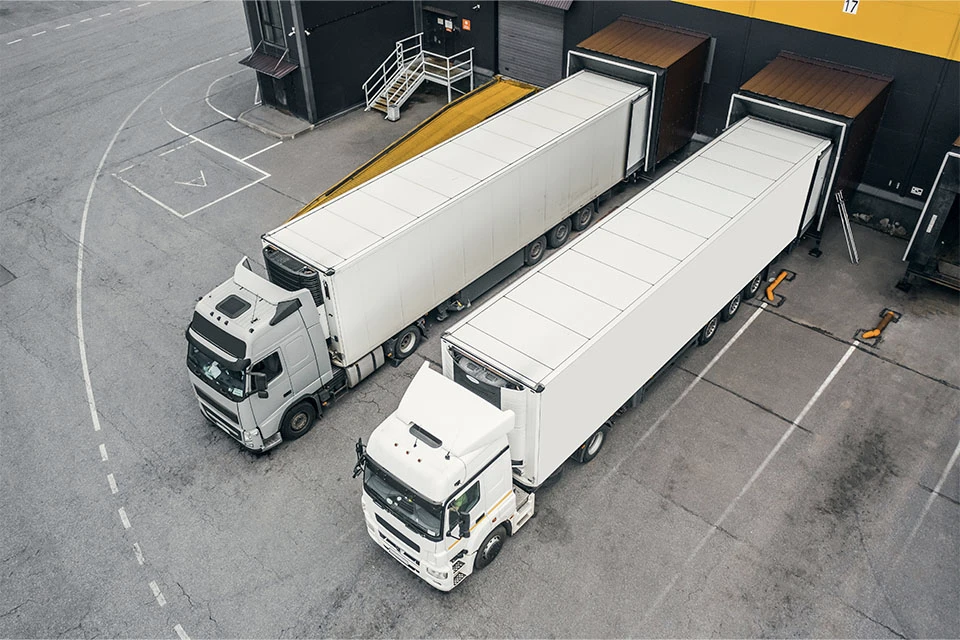 Two white trucks loading at a cargo depo